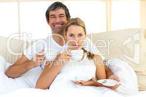 Intimate couple drinking coffee lying in the bed