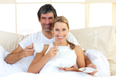 Affectionate couple drinking coffee lying in the bed