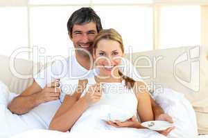 Affectionate couple drinking coffee lying in the bed