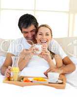 Loving couple having breakfast lying in the bed