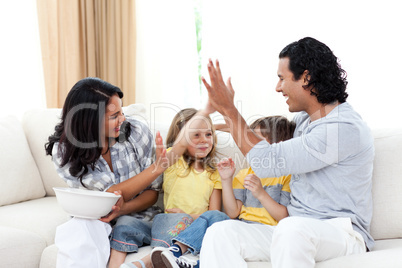 Joyful family watching TV on sofa
