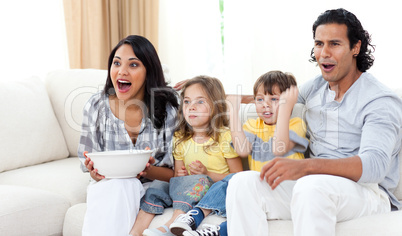 Cute siblings watching TV with their parents