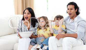 Cute siblings watching TV with their parents