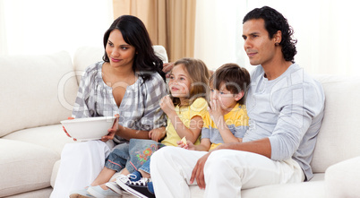 Smiling family watching TV on sofa