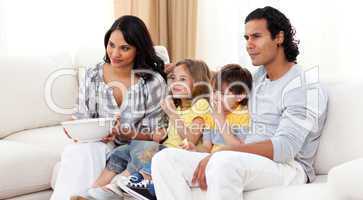 Smiling family watching TV on sofa