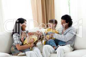 Earing parents playing with their children on sofa