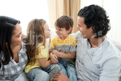 Cute siblings sitting on sofa with their parents Cute siblings sitting on sofa with their parents