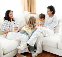 Attentive parents sitting on sofa with their children