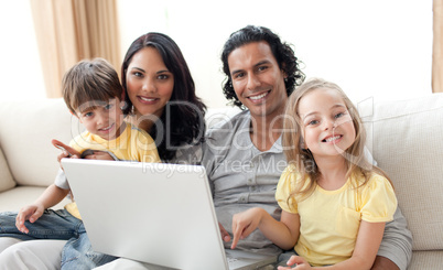 Jolly family using laptop on sofa