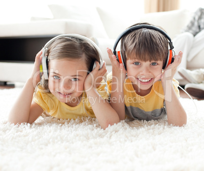 Smiling siblings listening music with headphones