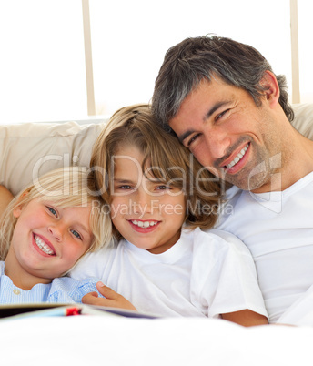 Smiling father and his children reading book