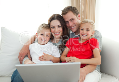 Jolly family using a computer sitting on sofa