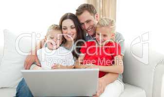 Joyful family using a computer sitting on sofa