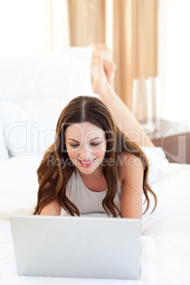 Attractive woman using her laptop lying on bed