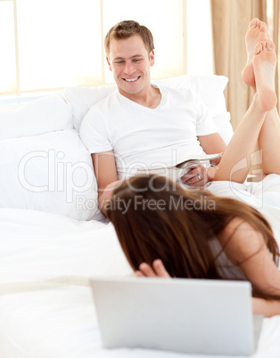 Enamoured woman with her husband working at a laptop