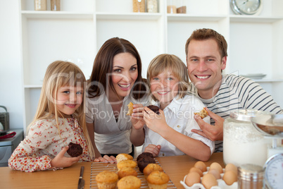 Cute children eating muffins with their parents