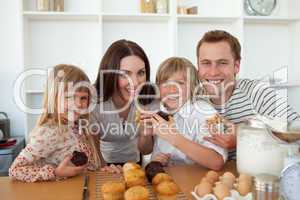 Cute children eating muffins with their parents