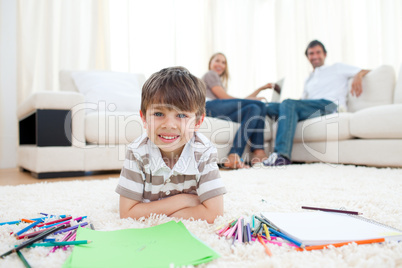 Adorable little boy drawing lying on the floor