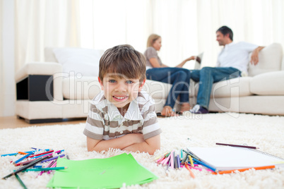 Smiling child drawing lying on the floor