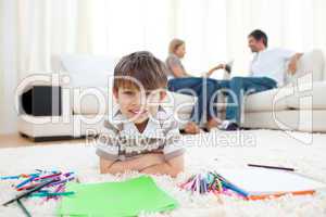 Smiling child drawing lying on the floor