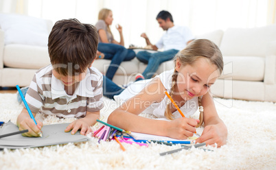 Concentrated siblings drawing lying on the floor