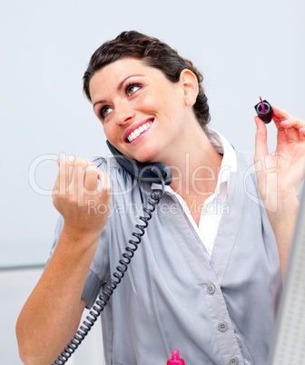 Charming woman on phone painting her nails