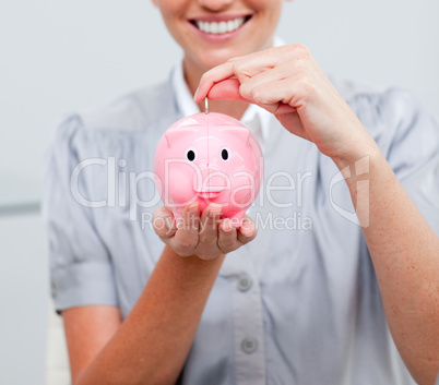 Attractive business woman inserting coin in a piggybank