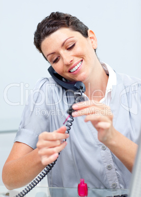 Pretty woman on phone painting her nails