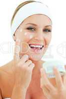 Caucasian woman putting cosmetic cream
