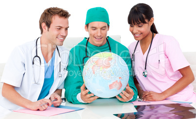 Cheerful medical team looking at terrestrial globe