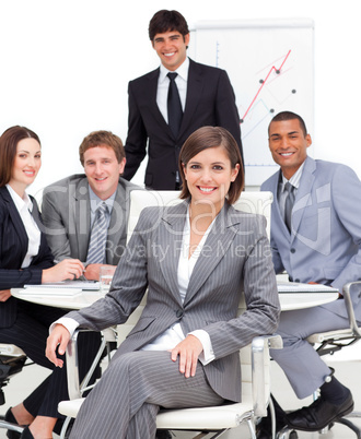 Assertive female executive sitting in front of her team