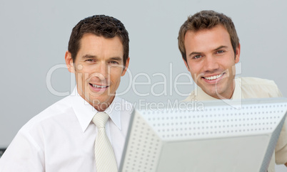 Smiling businessmen working together at a computer