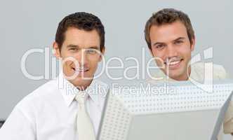 Smiling businessmen working together at a computer