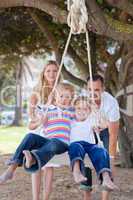 Joyful parents pushing their children on a swing
