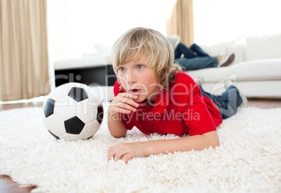Animated boy watching football match lying on the floor