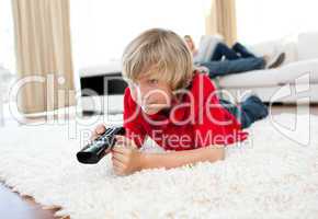 Cute boy holding a remote lying on the floor