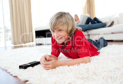 Concentrated boy watching TV lying on the floor