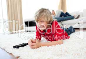 Concentrated boy watching TV lying on the floor