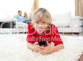 Smiling boy watching TV lying on the floor