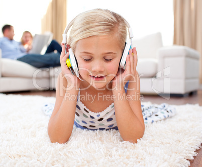 Cute little girl listening music lying on the floor