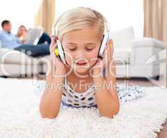 Cute little girl listening music lying on the floor