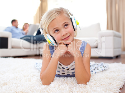 Adorable little girl listening music lying on the floor