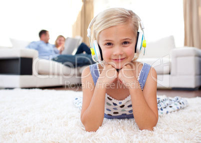 Smiling little girl listening music lying on the floor