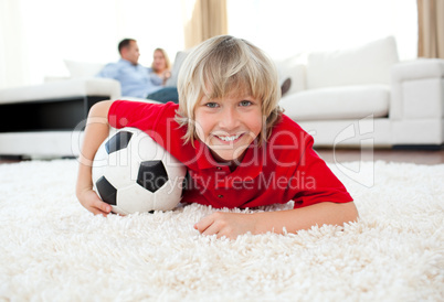 Smiling boy watching football match lying on the floor