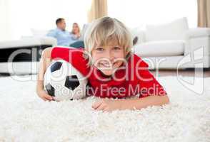 Smiling boy watching football match lying on the floor