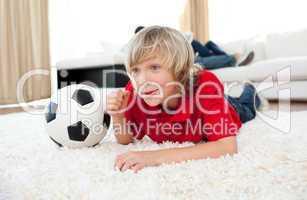 Excited boy watching football match lying on the floor