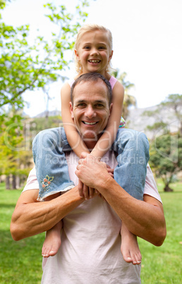 Smiling father giving his daughter piggy-back ride