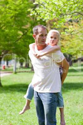 Joyful father giving his daughter piggy-back ride