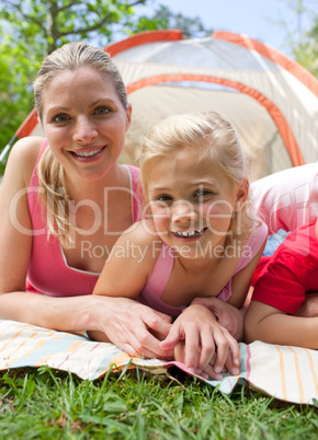 Carring mother and her little girl lying on the grass