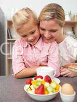 Adorable little girl eating fruit with her mother